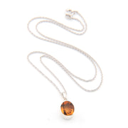 Silver necklace with a round citrine pendant on a white background