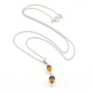 Silver necklace with two citrine teardrop pendants on a white background