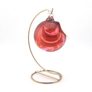 Pink glass ornament with a gold stand on a white background
