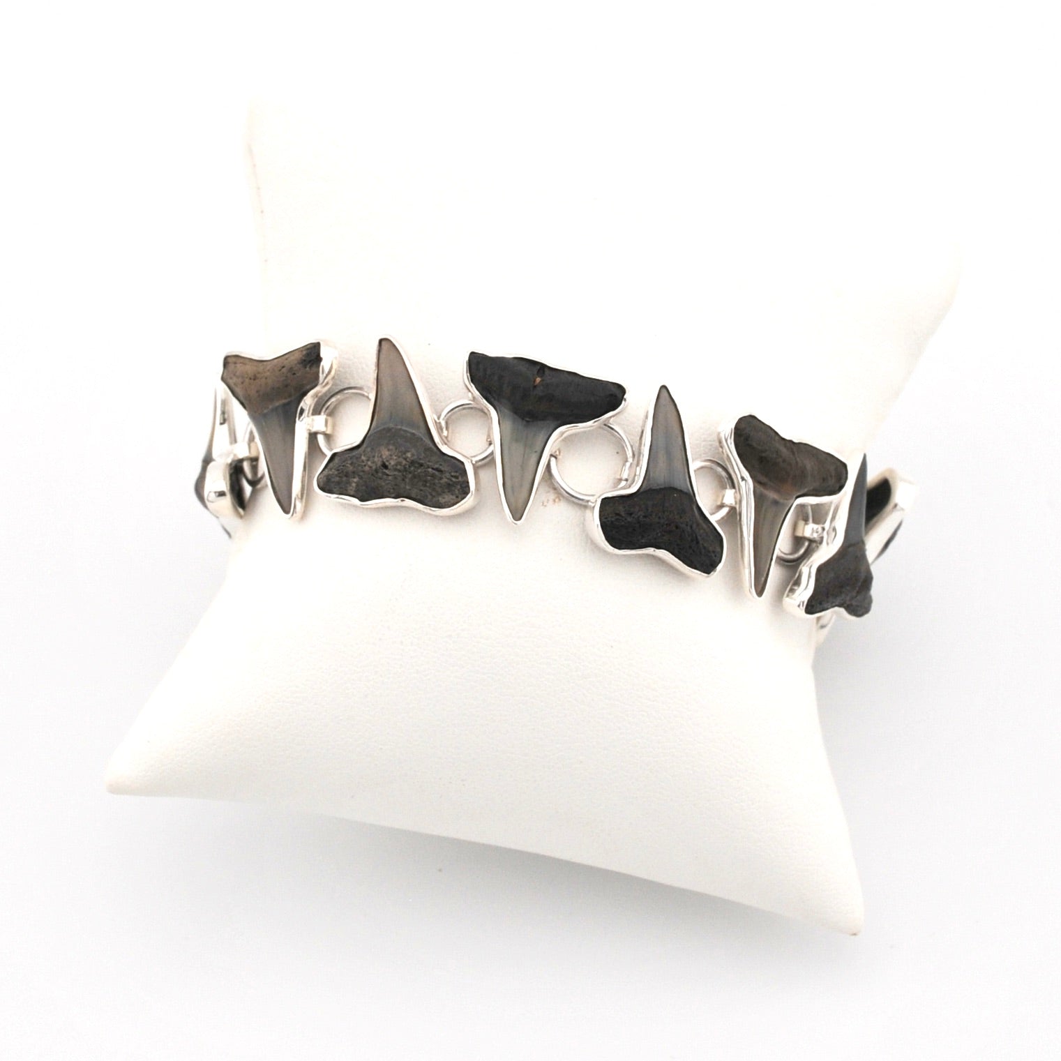 Silver bracelet with shark teeth on a white cushion