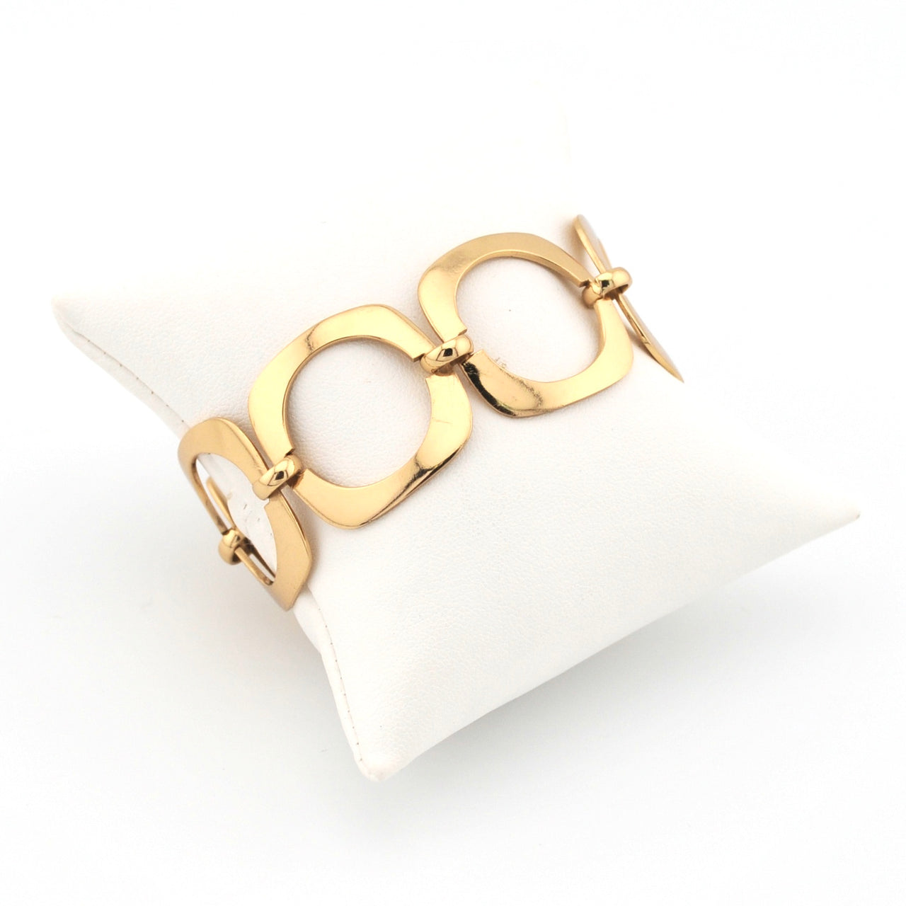 Gold link bracelet on a white jewelry cushion