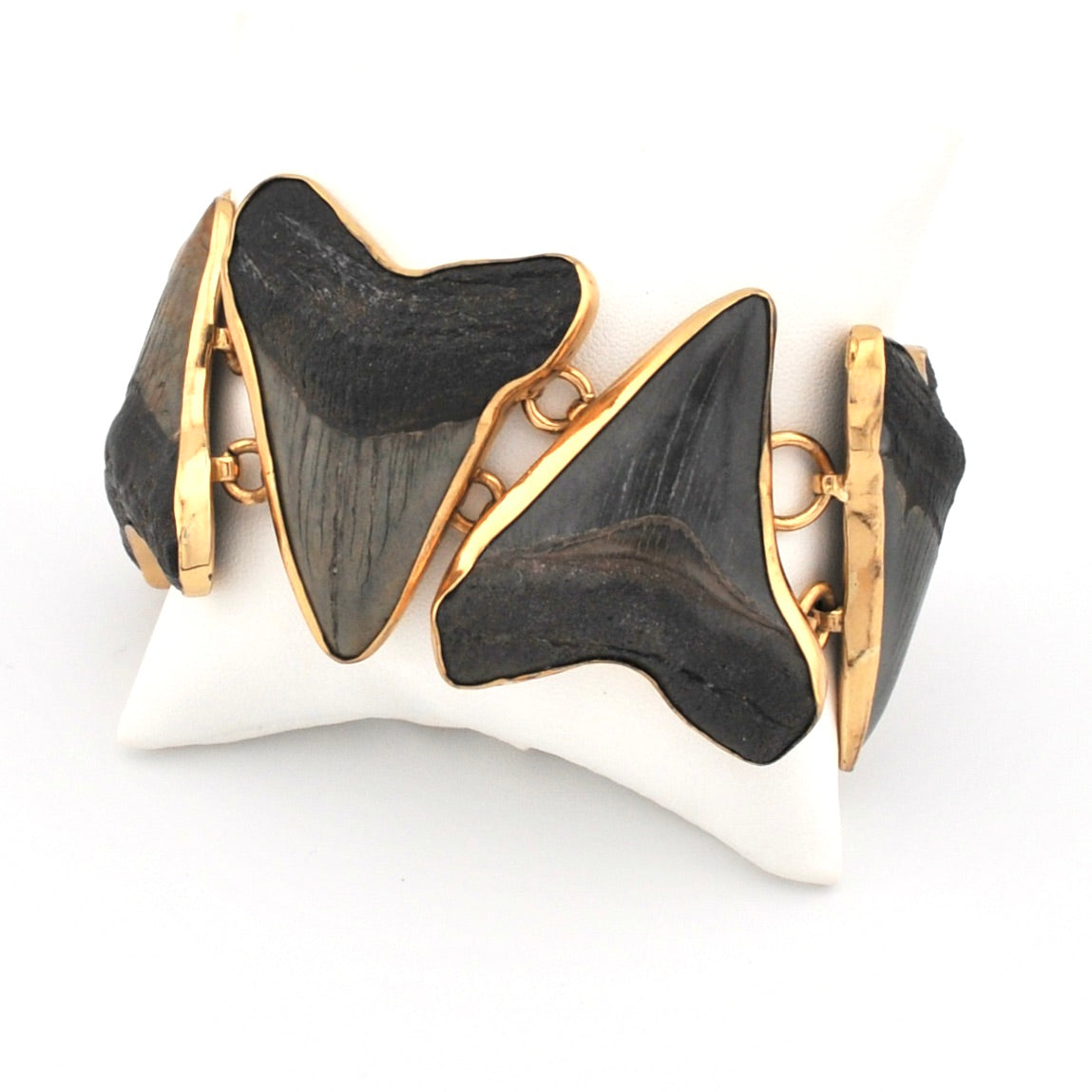 Bracelet with black shark teeth in a gold setting on a white background