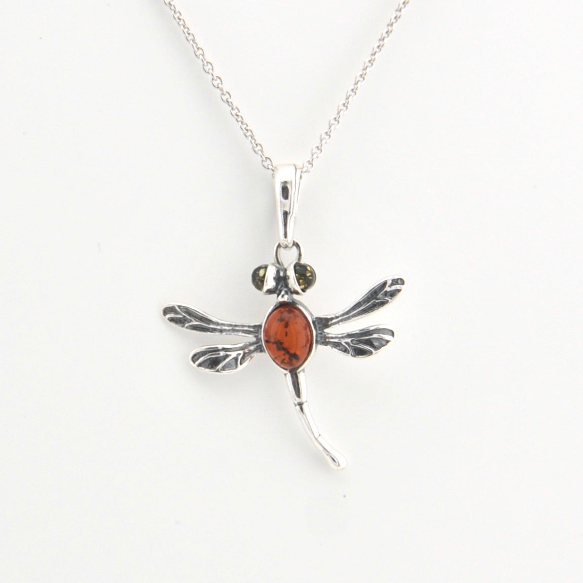 Silver dragonfly pendant with a red stone on a white background