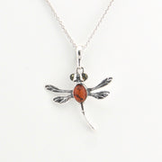 Silver dragonfly pendant with a red stone on a white background