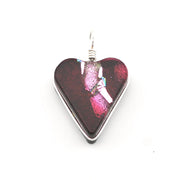 A heart-shaped glass pendant with a dark red and magenta iridescent center, bordered by a silver metal frame and topped with a silver wire loop, shown on a plain white background.
