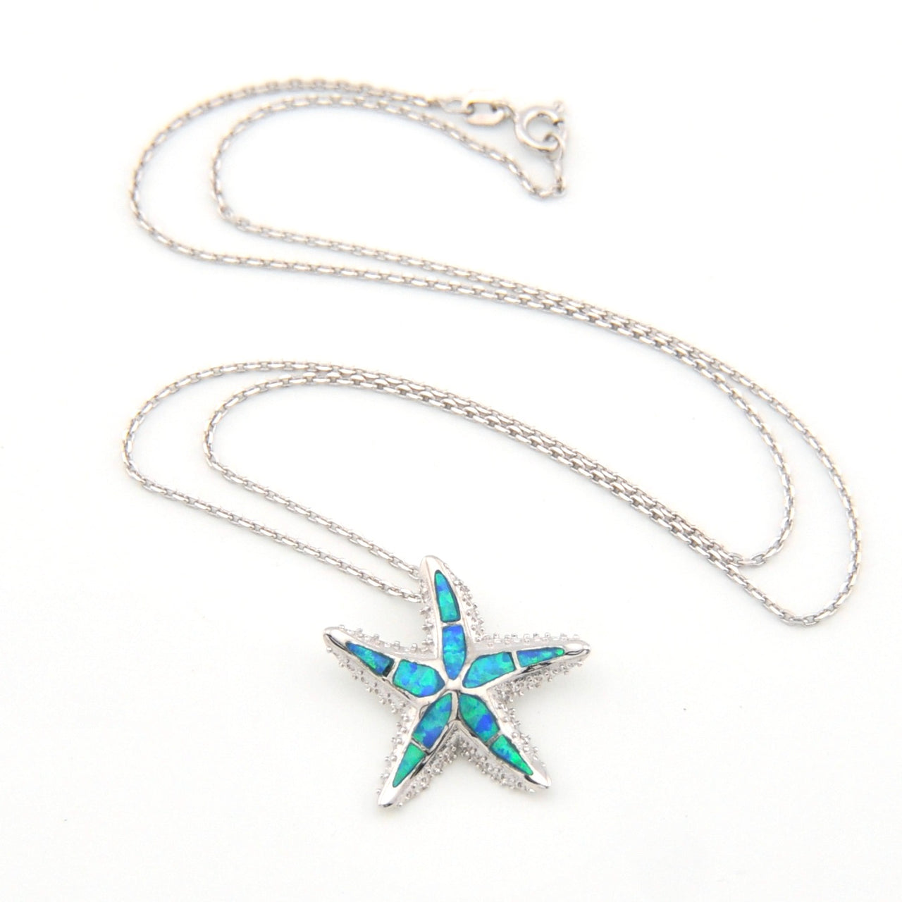 Starfish-shaped pendant with blue opal inlay on a silver chain against a white background