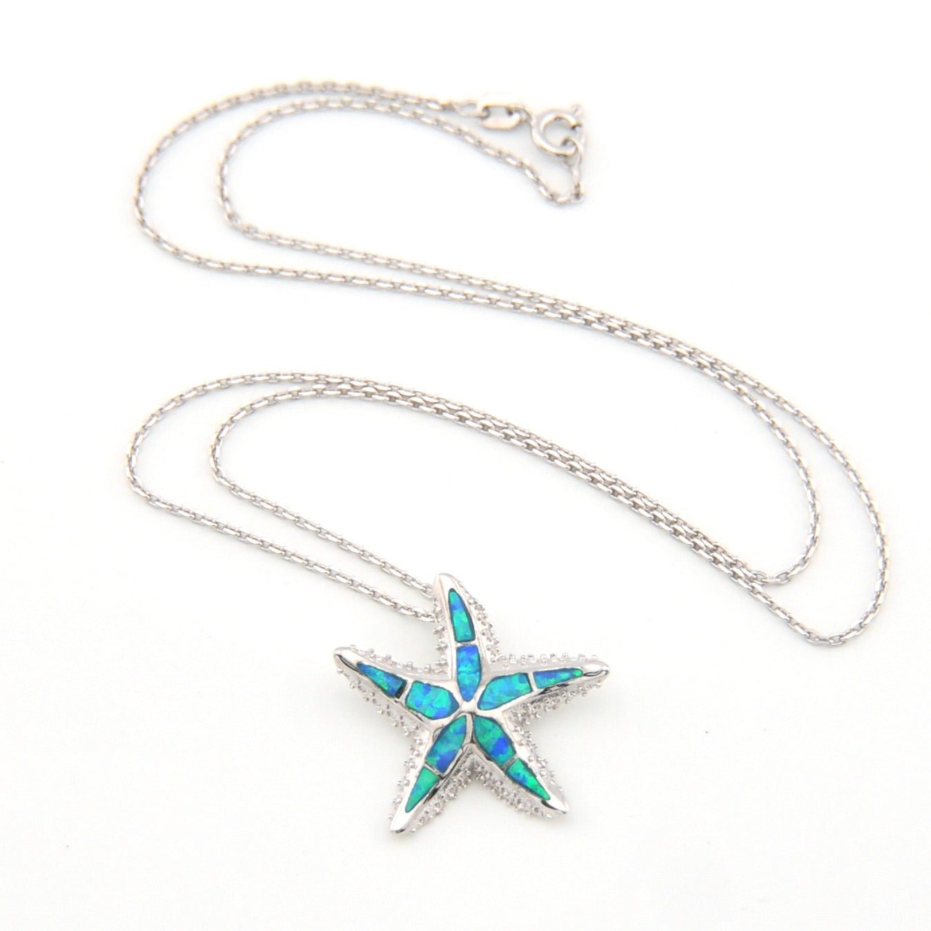 Starfish-shaped pendant with blue opal inlay on a silver chain against a white background