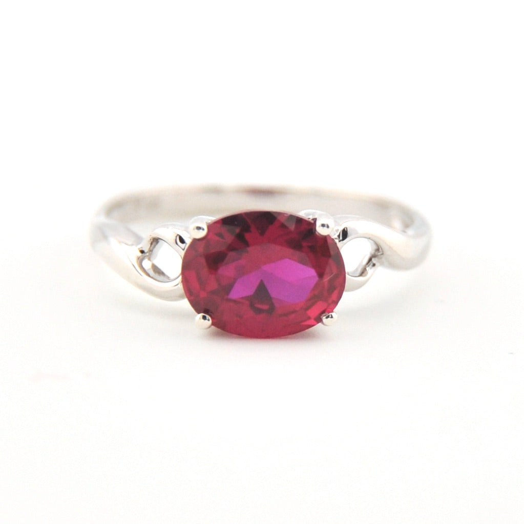 Silver ring with a red gemstone on a white background