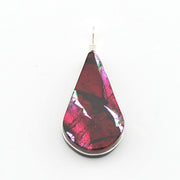 A teardrop-shaped glass pendant featuring a marbled pattern of deep red, magenta, and black, suspended from a silver wire on a plain white background.