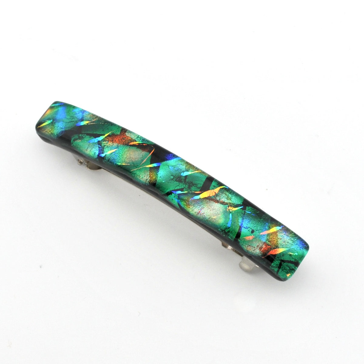 A rectangular hair barrette featuring a vibrant, iridescent dichroic glass with shimmering green, blue, orange, and black colors, set against a plain white background.