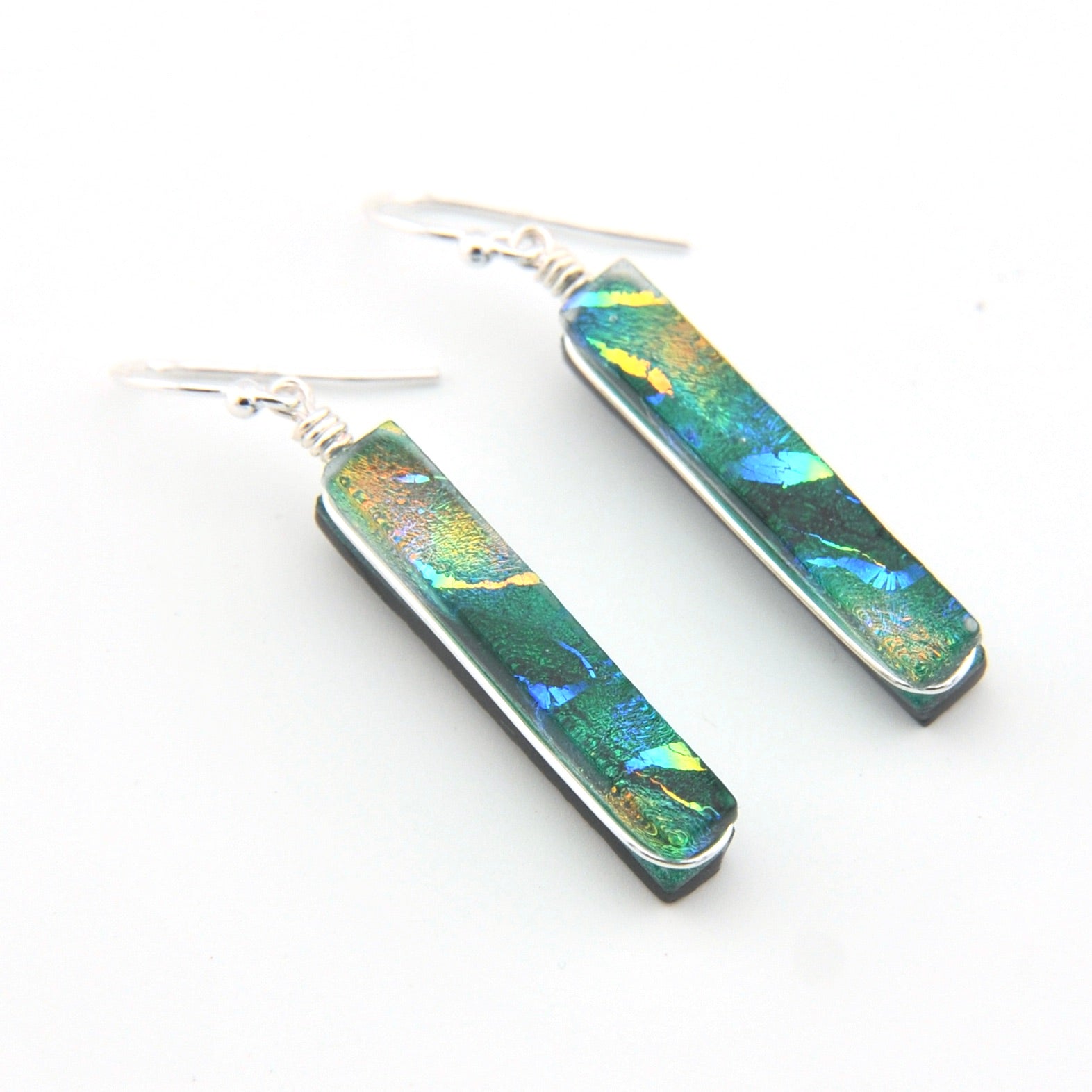 Pair of earrings with green and blue iridescent design on a white background