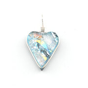 A heart-shaped glass pendant with a silver wire-wrapped setting, featuring a multicolored fusing pattern of light blue, yellow, orange, and black on a white background.
