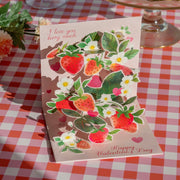Valentine's Day card with strawberry design on a checkered tablecloth
