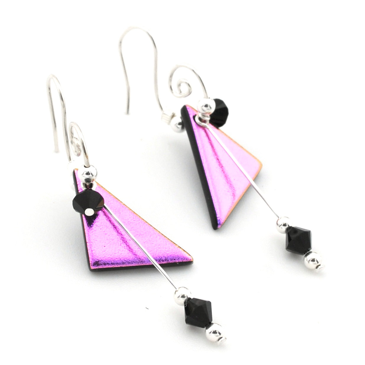 A pair of geometric dangle earrings featuring textured, metallic purple and pink triangular charms, silver wire hooks, and small black faceted beads on a white background.