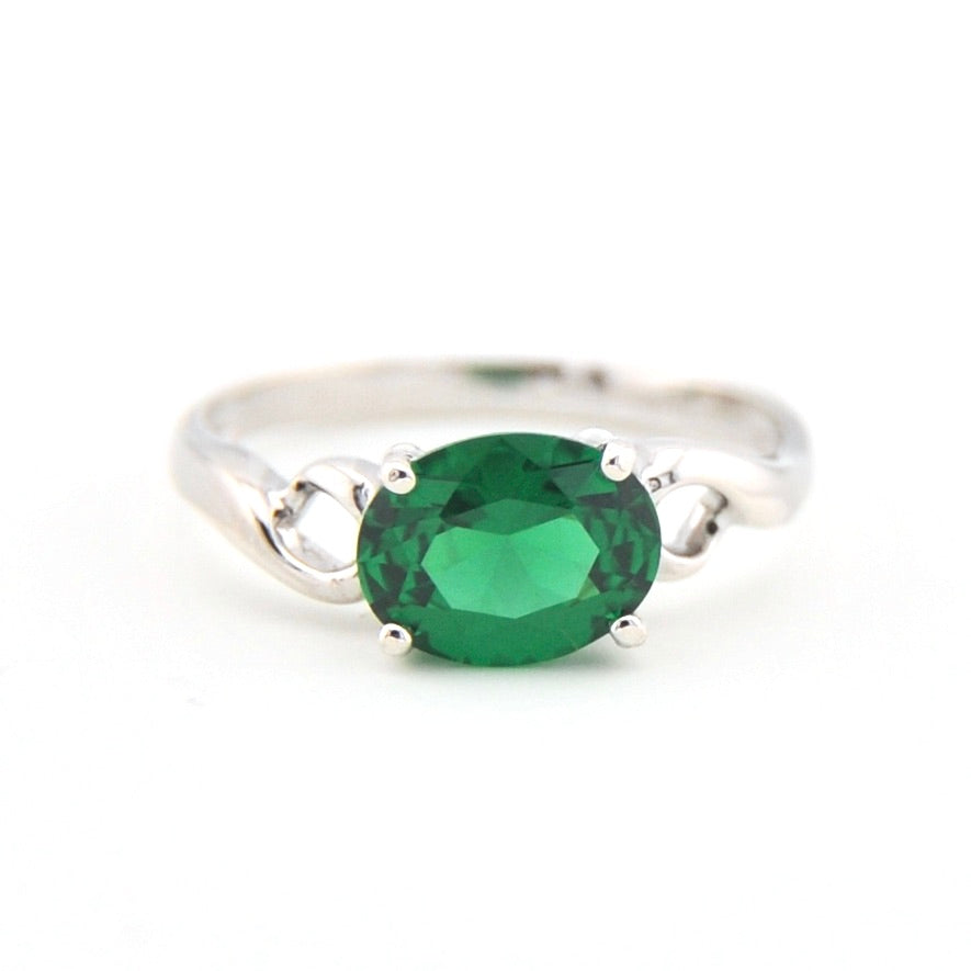 Silver ring with a green gemstone on a white background