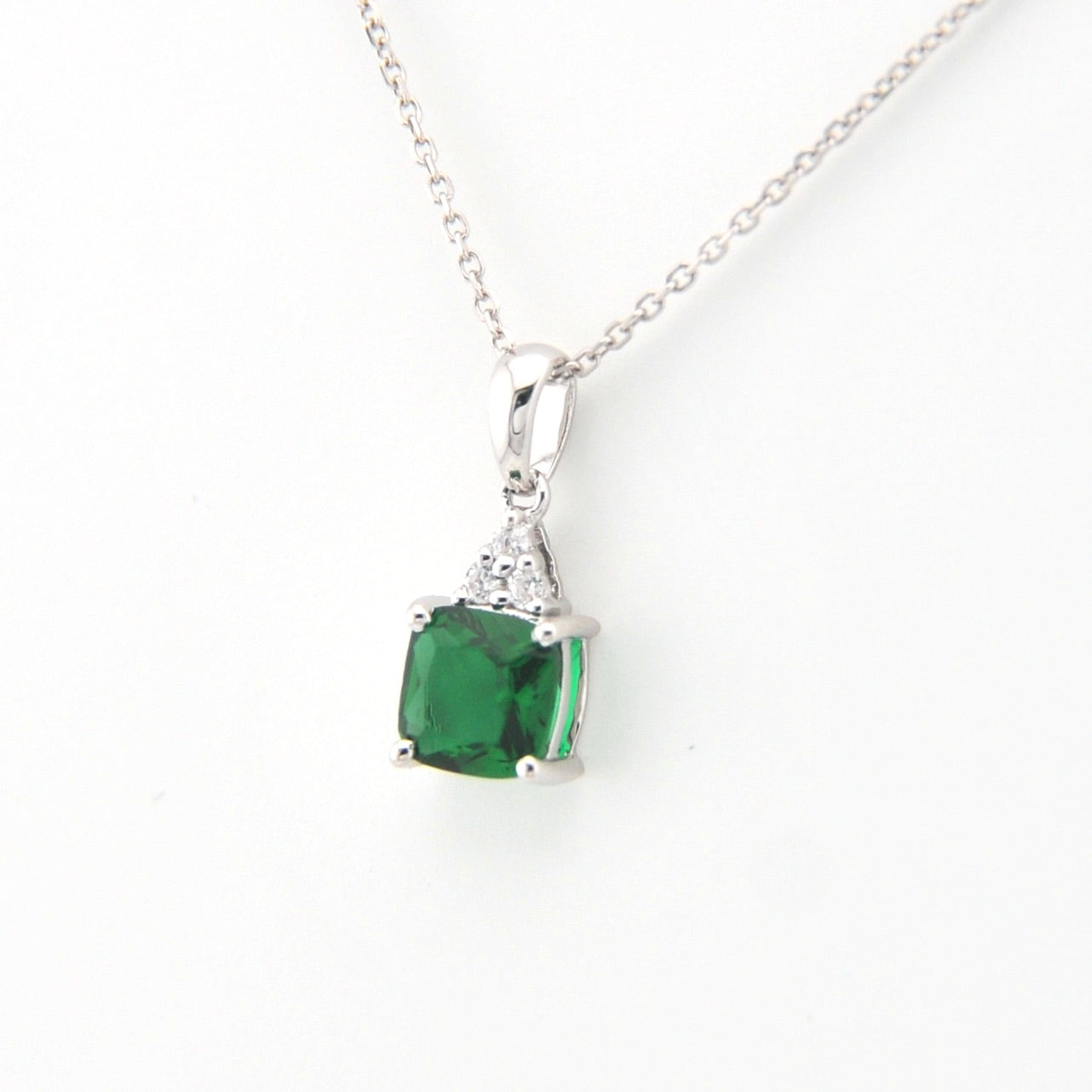 Green gemstone pendant on a silver chain against a white background