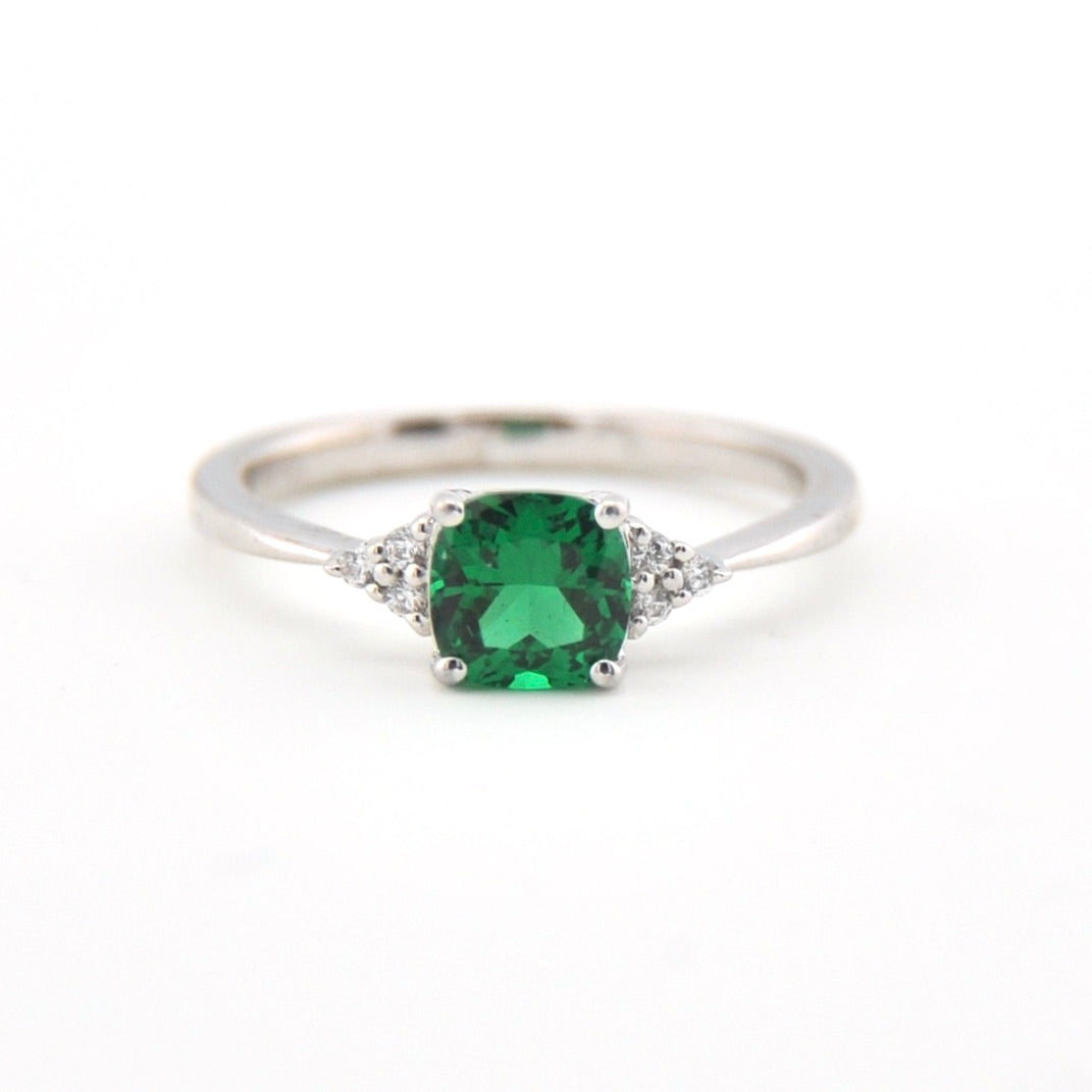 Silver ring with a green gemstone on a white background