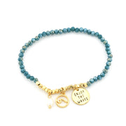 Crystal stretch bracelet with gold wave charm and charm that say "Enjoy the waves."
