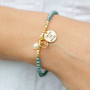 Crystal stretch bracelet with wave charms on wrist.