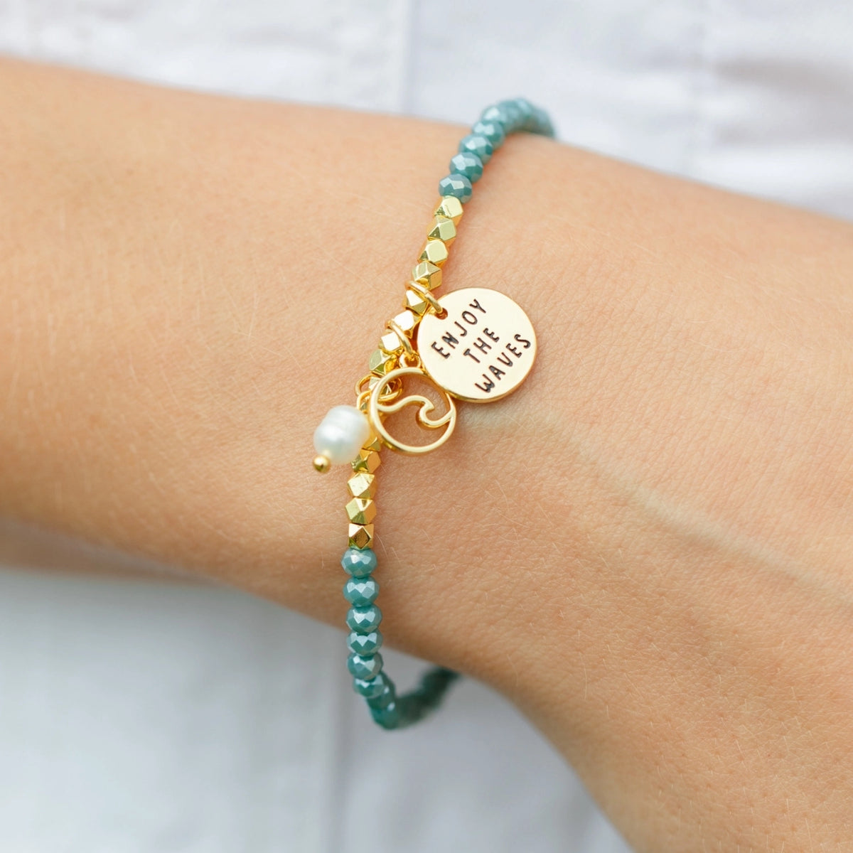 Crystal stretch bracelet with wave charms on wrist.