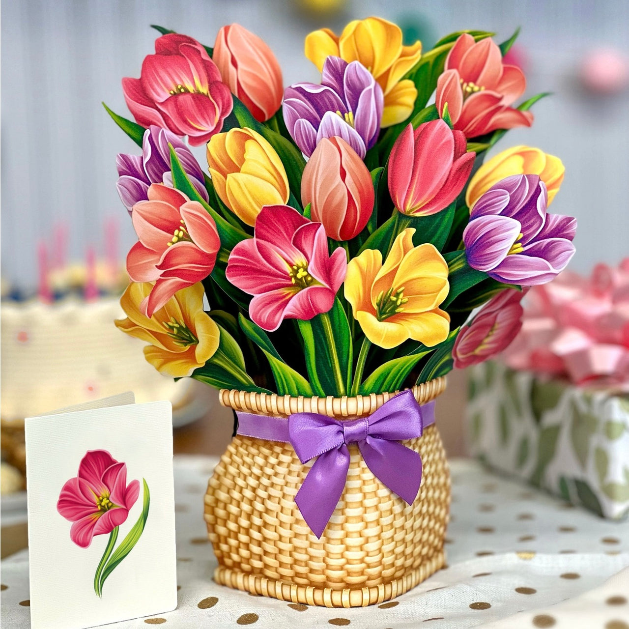 Bouquet of colorful tulips in a woven basket with a purple ribbon, on a polka dot tablecloth.