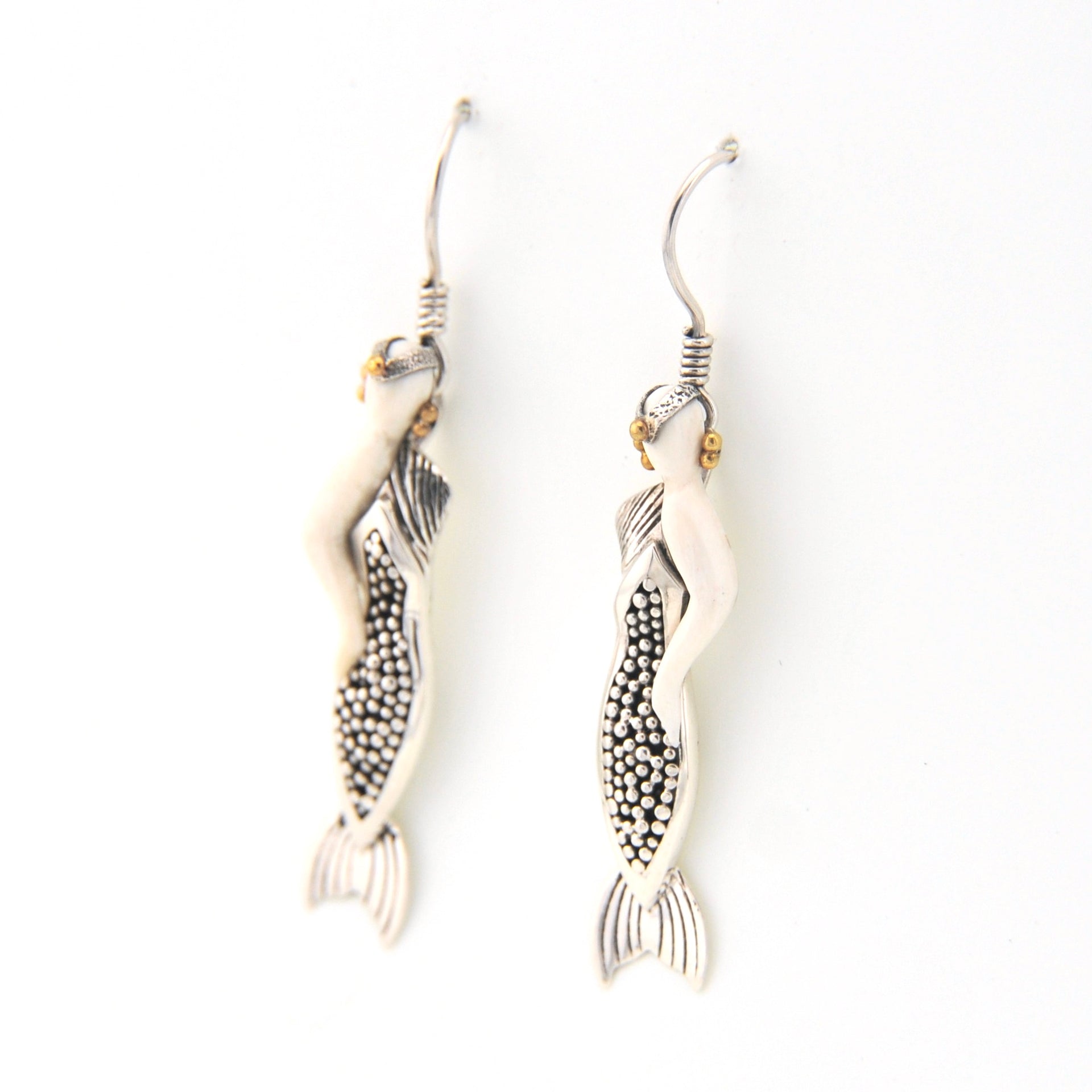 Pair of mermaid earrings with intricate designs on a white background