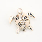 Silver turtle pendant with black patterns on a white background