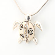 Silver turtle pendant with spiral patterns on a white background