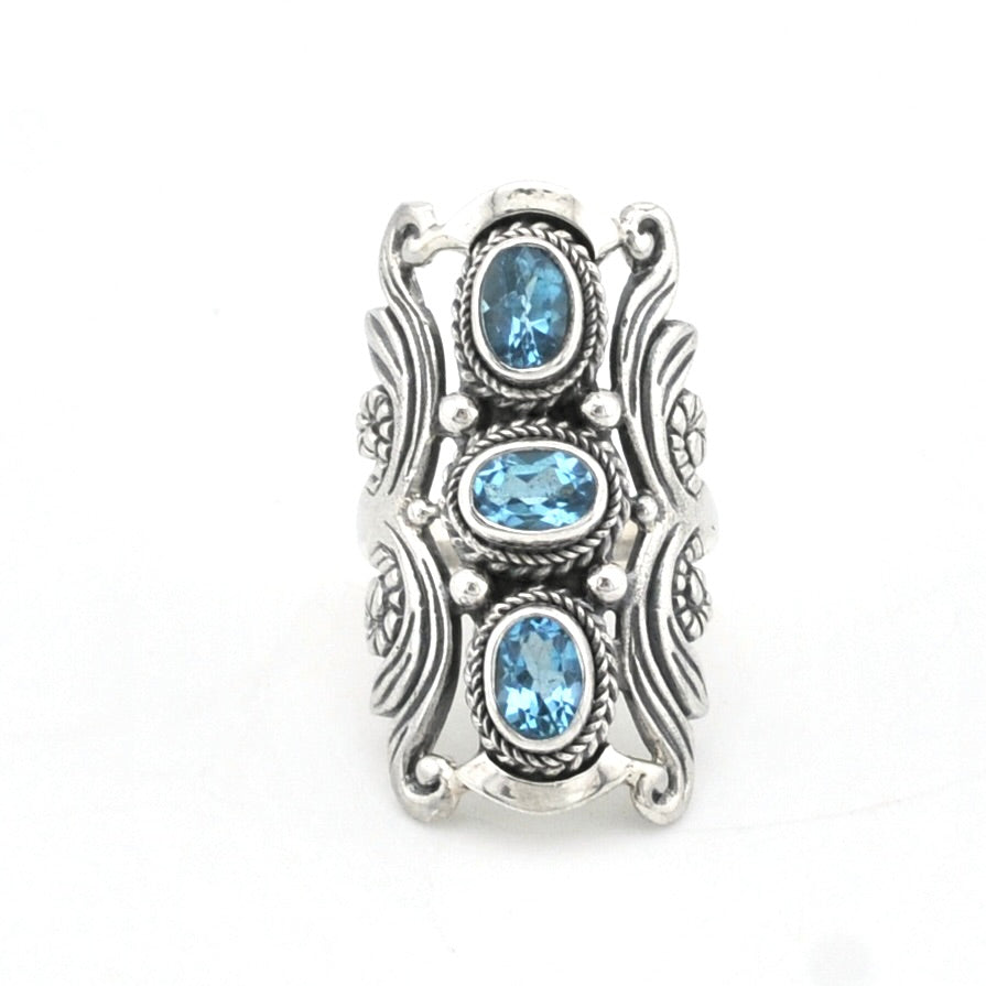 An ornate sterling silver ring featuring three oval-cut light blue gemstones set in a detailed, textured silver setting on a plain white background.