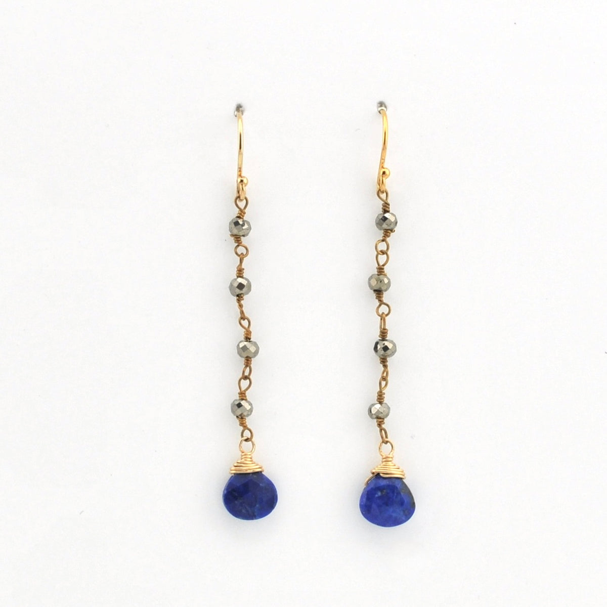 A pair of gold drop earrings with small metallic beads and a deep blue teardrop-shaped gemstone at the bottom, shown on a plain white background.