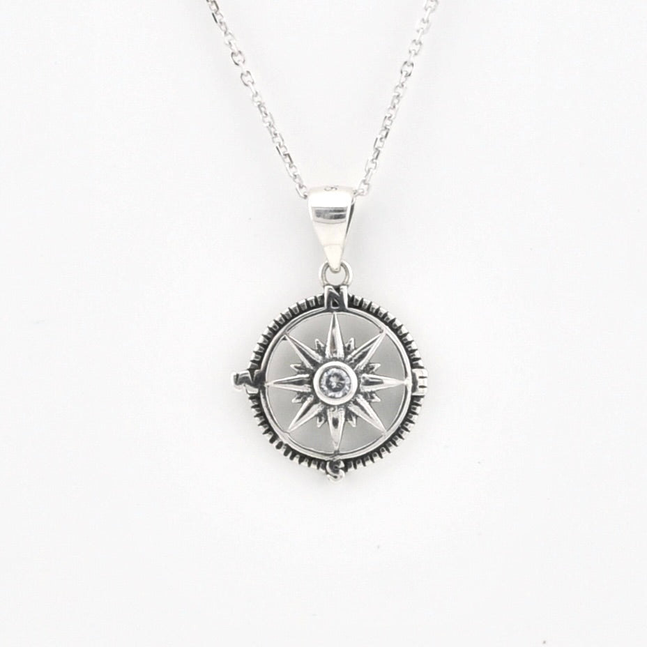 A silver compass pendant necklace on a delicate silver chain, displayed against a clean white background.