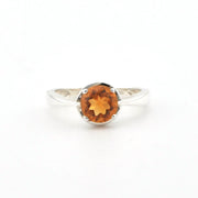 A silver ring with an oval-cut orange gemstone, photographed on a clean white background.