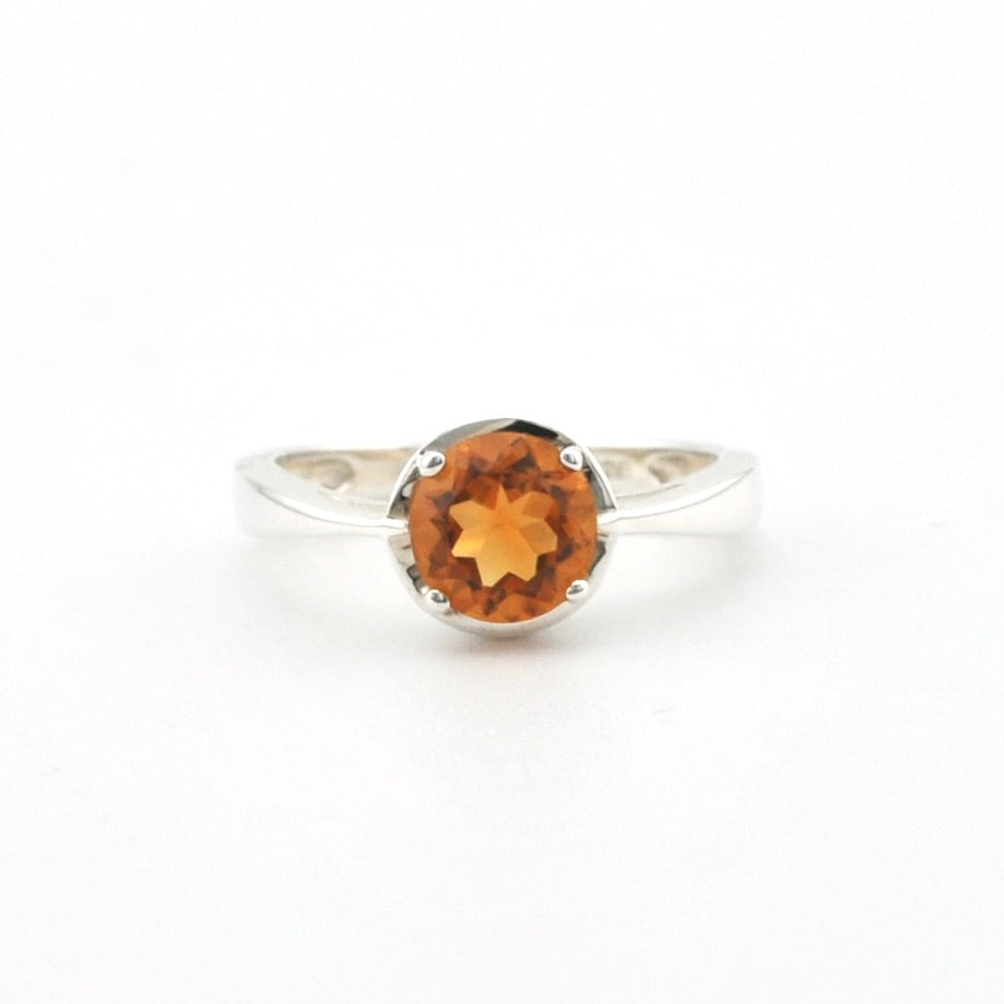 A silver ring with an oval-cut orange gemstone, photographed on a clean white background.