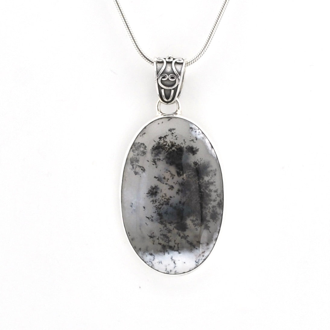 An oval pendant necklace featuring a black-and-white marbled stone with dendritic crystal patterns, set in a silver-toned bezel and suspended from a silver chain.