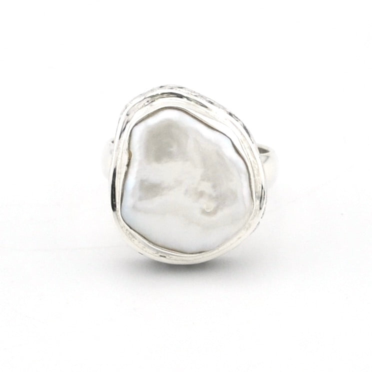 A sterling silver ring featuring a large, irregularly shaped white baroque pearl bezel-set in a textured, hand-drawn style silver frame, shown on a plain white background.