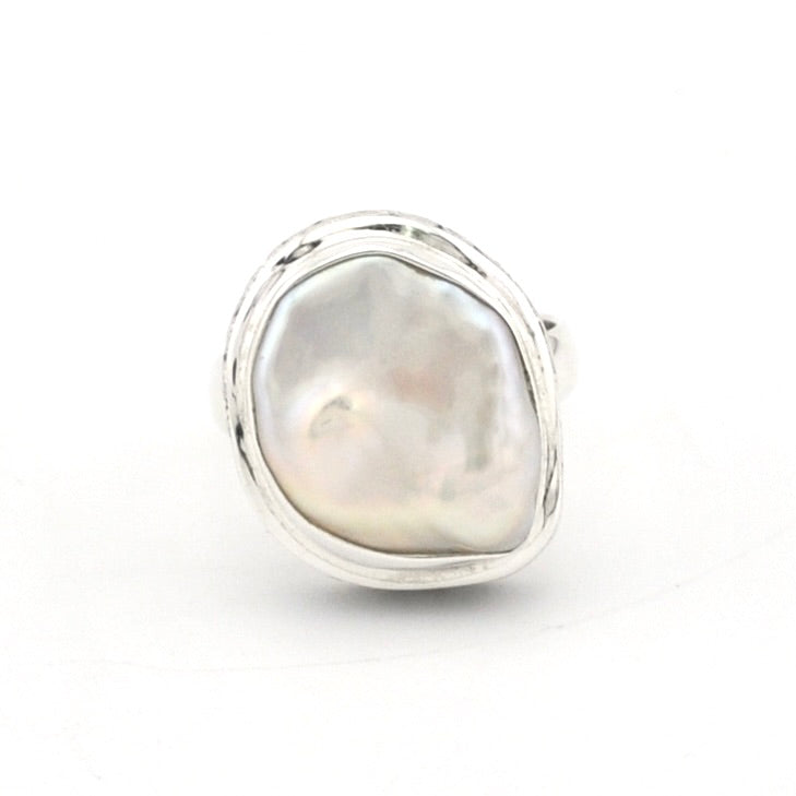 A sterling silver ring featuring a large, irregular baroque pearl with iridescent white and soft pinkish-gold tones, set in a polished bezel-style silver frame against a plain white background.