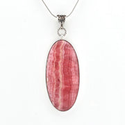 An oval pendant necklace featuring a pink and red striped mineral stone, set in a silver-toned bezel with a silver chain, shown against a plain white background.