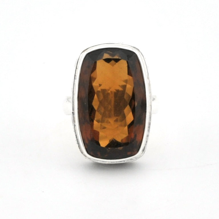A silver ring featuring a large, cushion-cut faceted brown gemstone, shown against a plain white background.