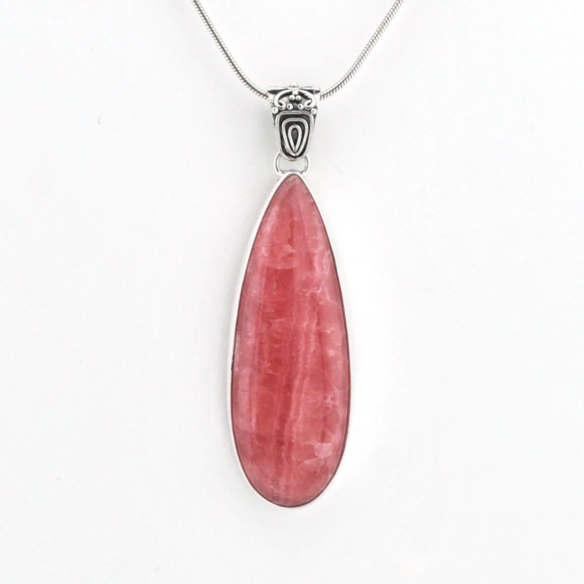 A teardrop-shaped pink gemstone pendant in a silver bezel setting on a silver chain, shown against a plain white background.