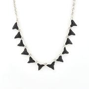 Silver necklace featuring 12 shark teeth on white background.