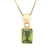 A yellow gold pendant necklace featuring a rectangular emerald-cut green gemstone, suspended from a matching gold chain against a plain white background.