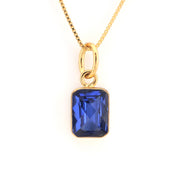 Gold necklace with a blue gemstone pendant on a white background