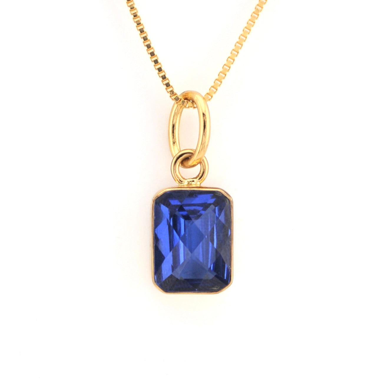 Gold necklace with a blue gemstone pendant on a white background