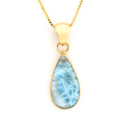 Gold necklace with a teardrop-shaped larimar pendant on a white background