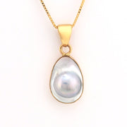 Gold pendant with a large pearl on a white background