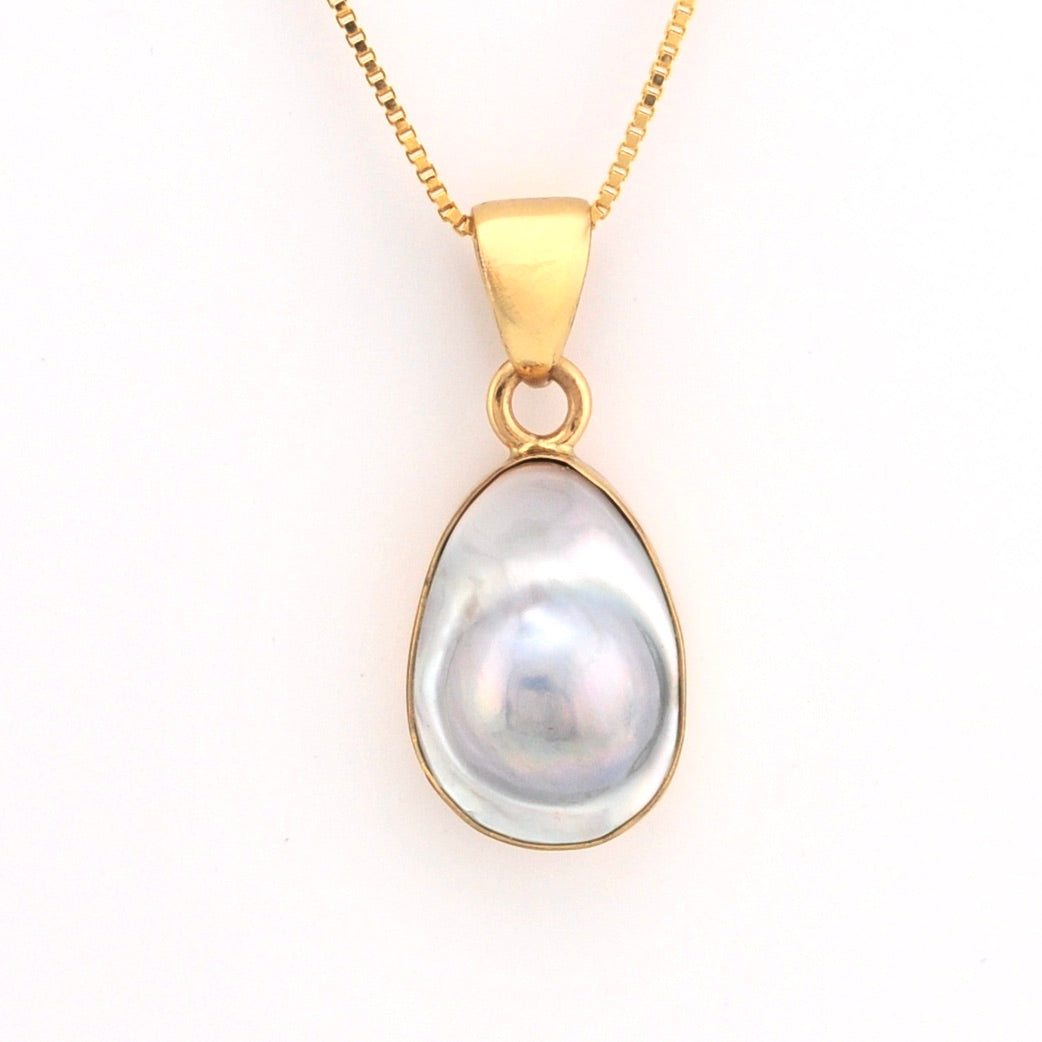 Gold pendant with a large pearl on a white background