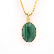 Gold necklace with a green malachite pendant on a white background