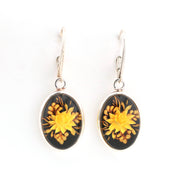 Pair of earrings with yellow floral design on a black background