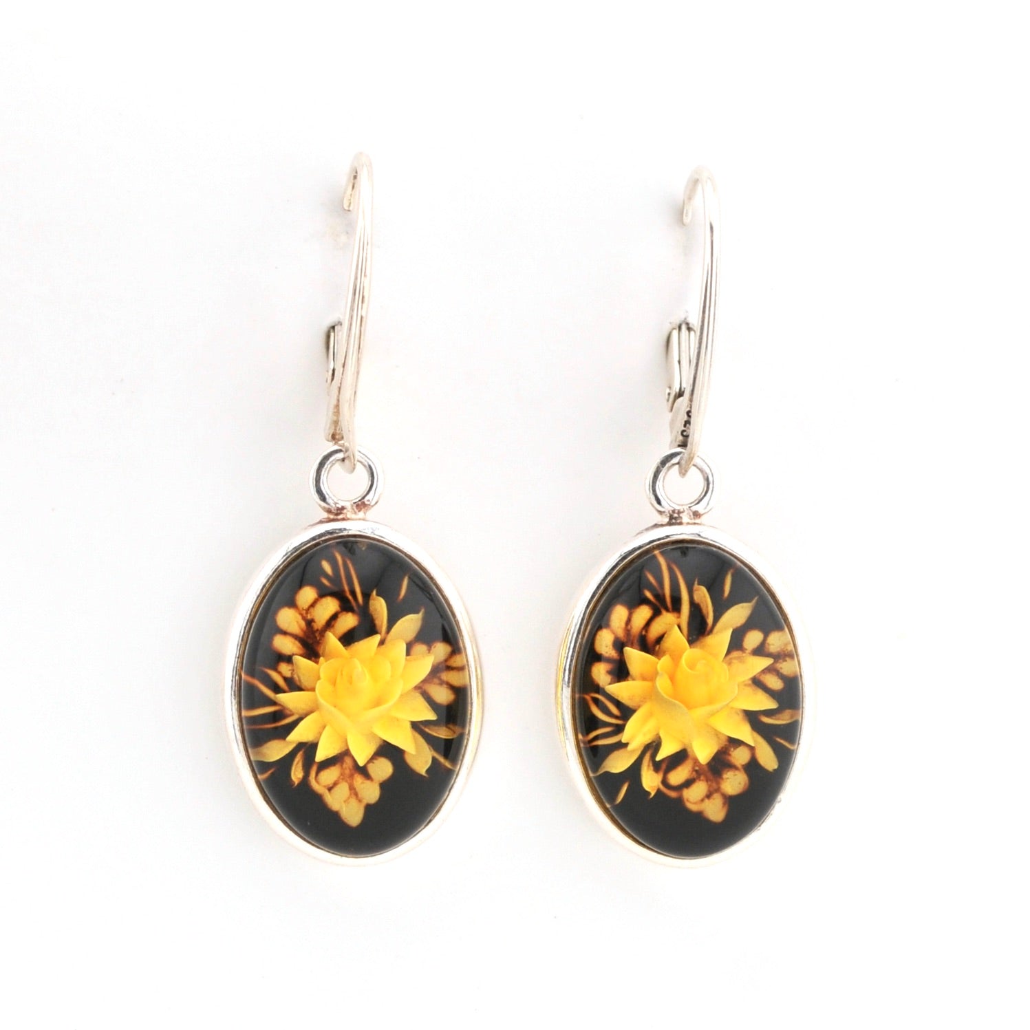 Pair of earrings with yellow floral design on a black background