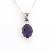Silver pendant with a purple gemstone on a white background
